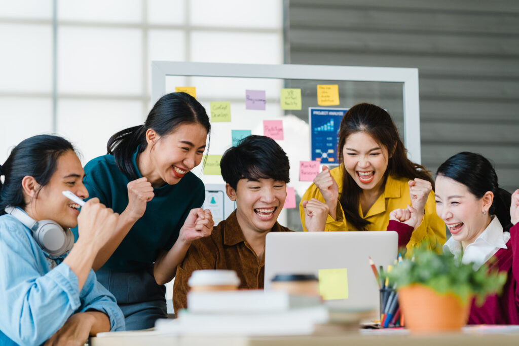 Group of Asia young creative people in smart casual wear discussing business celebrate giving five after dealing feeling happy and signing contract or agreement in office. Coworker teamwork concept.